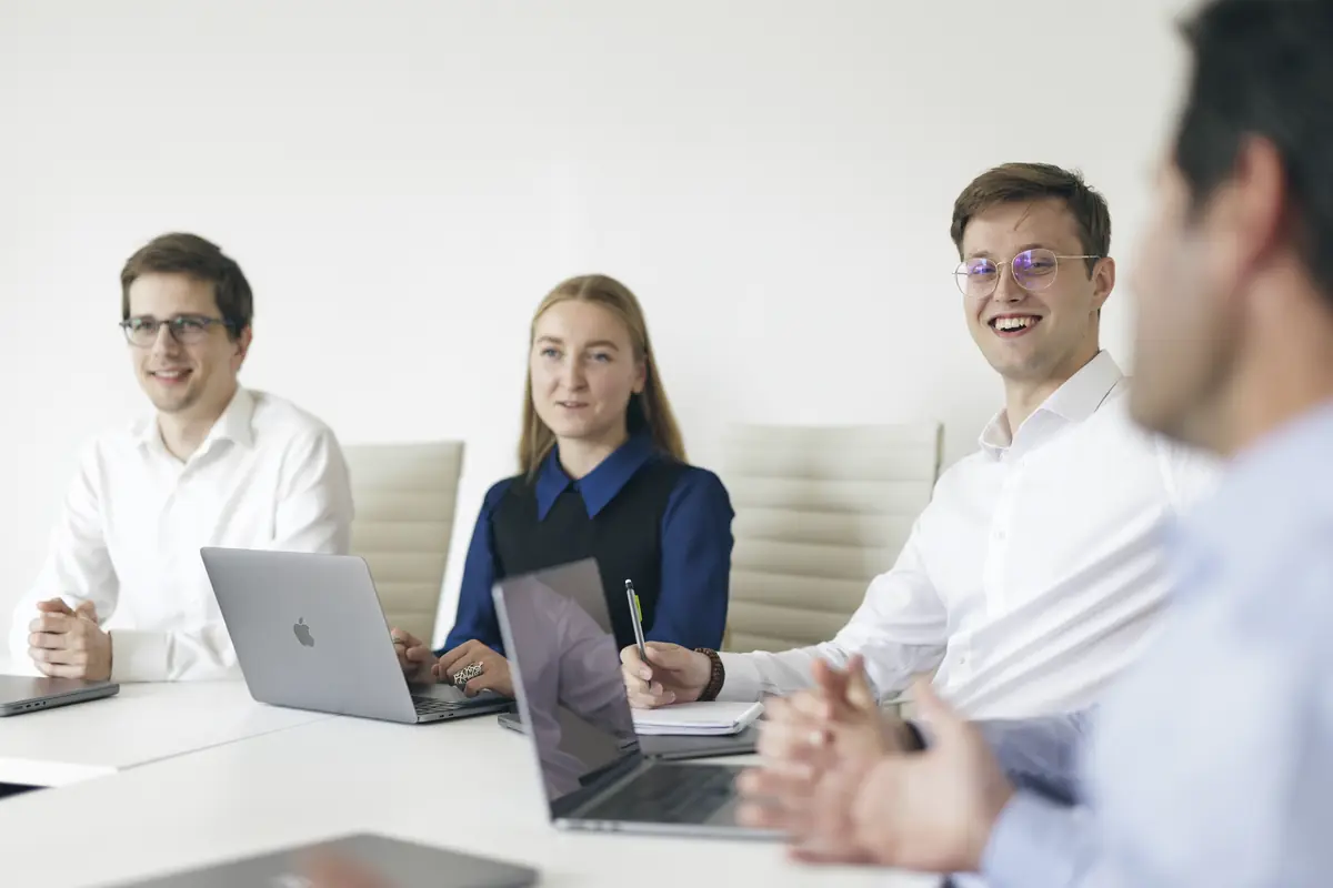 Consultores de Emerton Data sonríen durante una reunión de equipo alrededor de una mesa